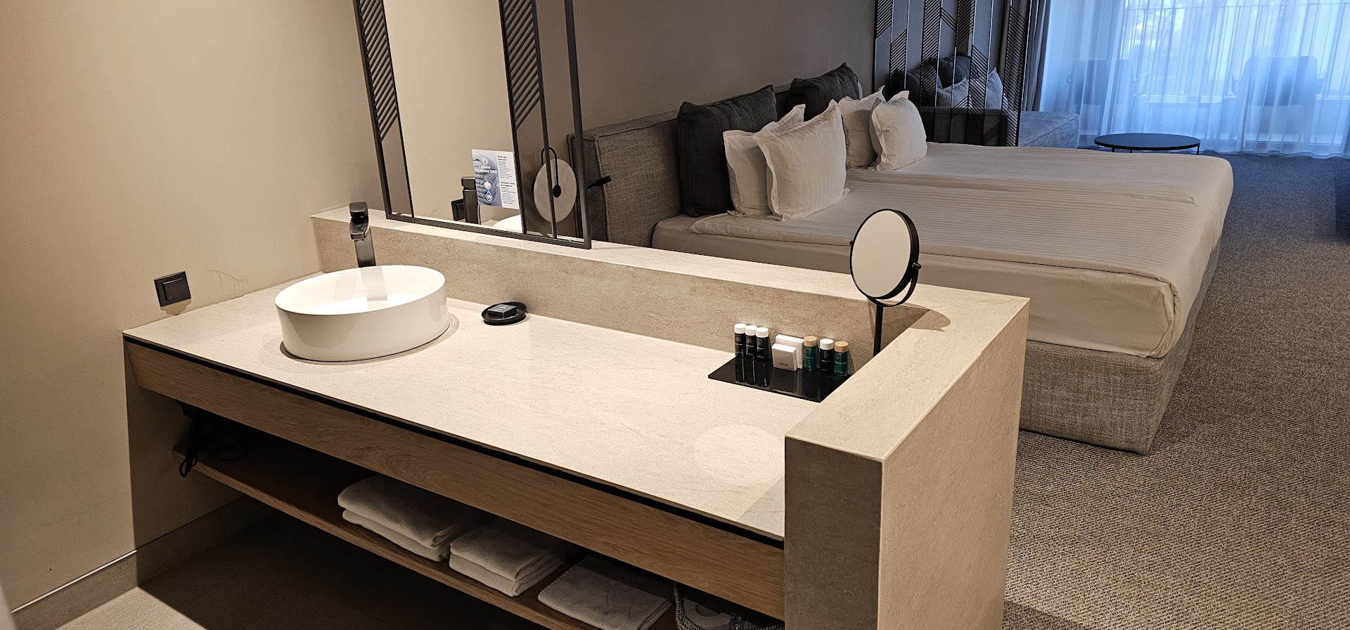 Aquahouse Hotel & SPA numura interjers ar atvērta plānojuma vannasistabas zonu, akmens virsmu un ērtu divguļamo gultu fonā