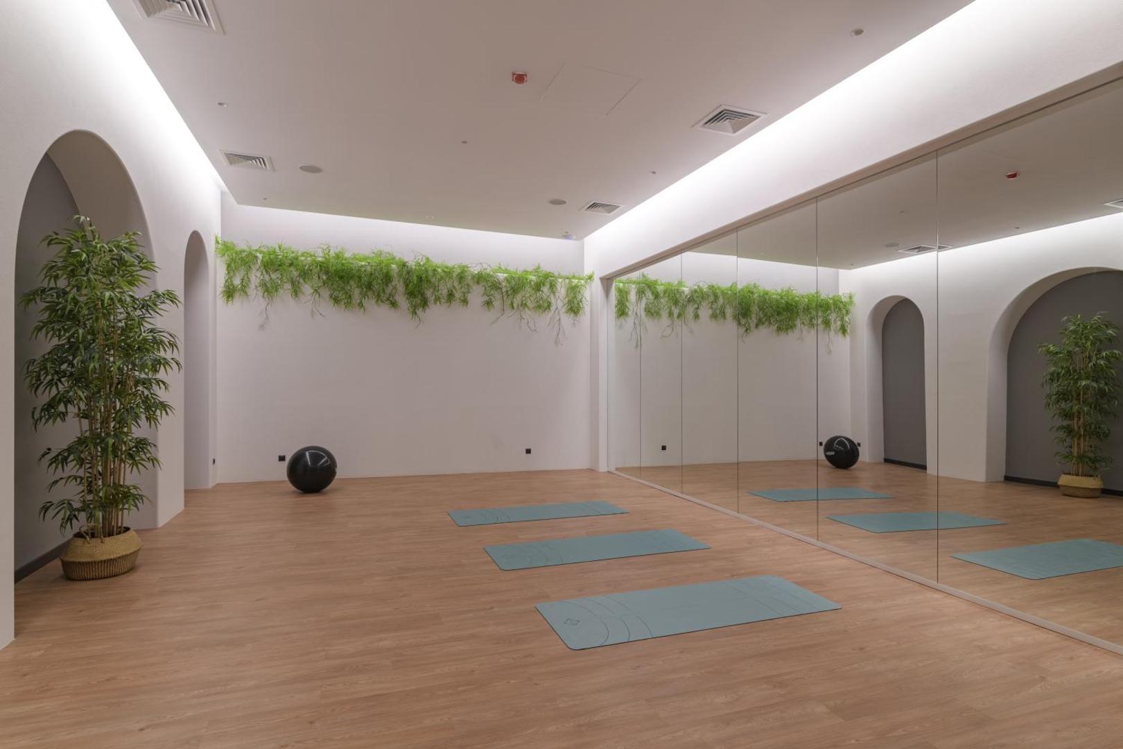 Aquahouse Hotel & SPA jogas un vingrošanas zāle ar spoguļsienu, koka grīdu un jogas paklājiņiem