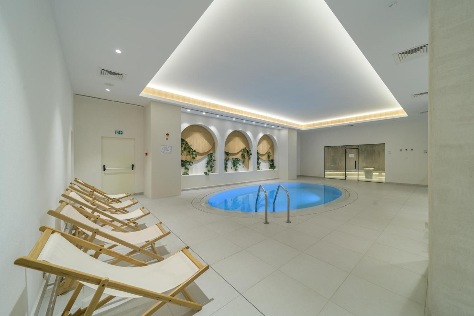 Aquahouse Hotel & SPA iekštelpu spa zona ar nelielu baseinu, atpūtas krēsliem un dekoratīviem augiem pie sienām