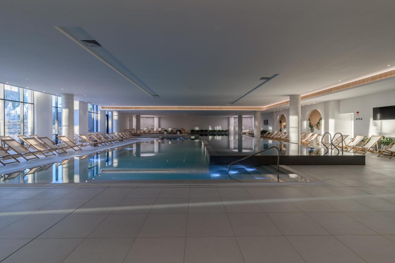 Aquahouse Hotel & SPA plašs iekštelpu spa baseins ar modernu apgaismojumu un daudziem atpūtas krēsliem relaksācijai piekrastē