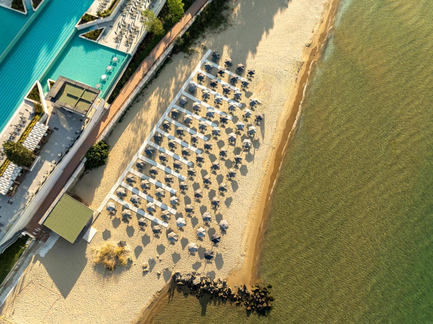 Aerofoto skats uz Secrets Sunny Beach Resort and Spa privāto pludmali ar saulessargiem un dzidru jūras ūdeni