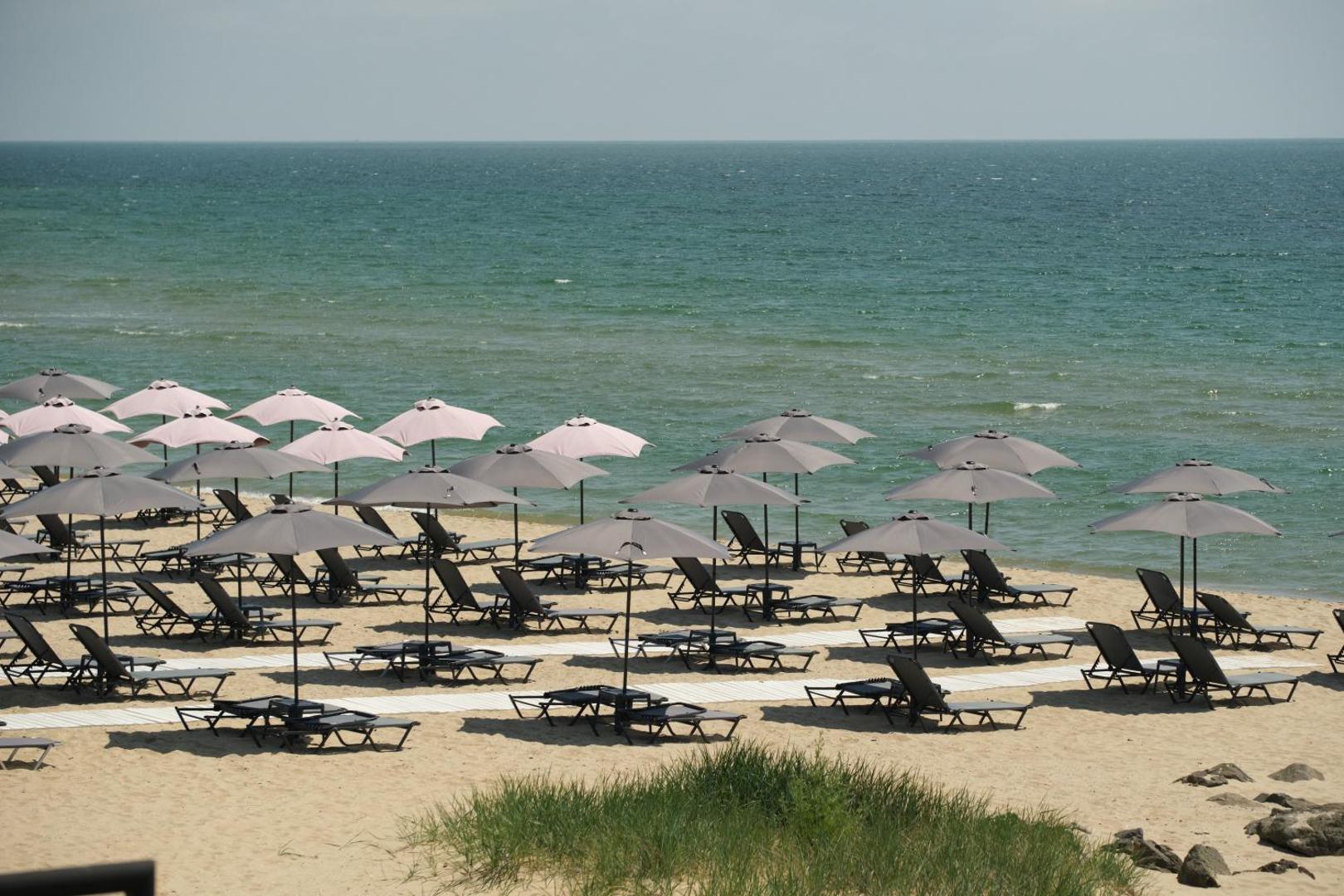 Skats no augšas uz Secrets Sunny Beach Resort and Spa pludmali ar daudziem saulessargiem un sauļošanās krēsliem pie jūras