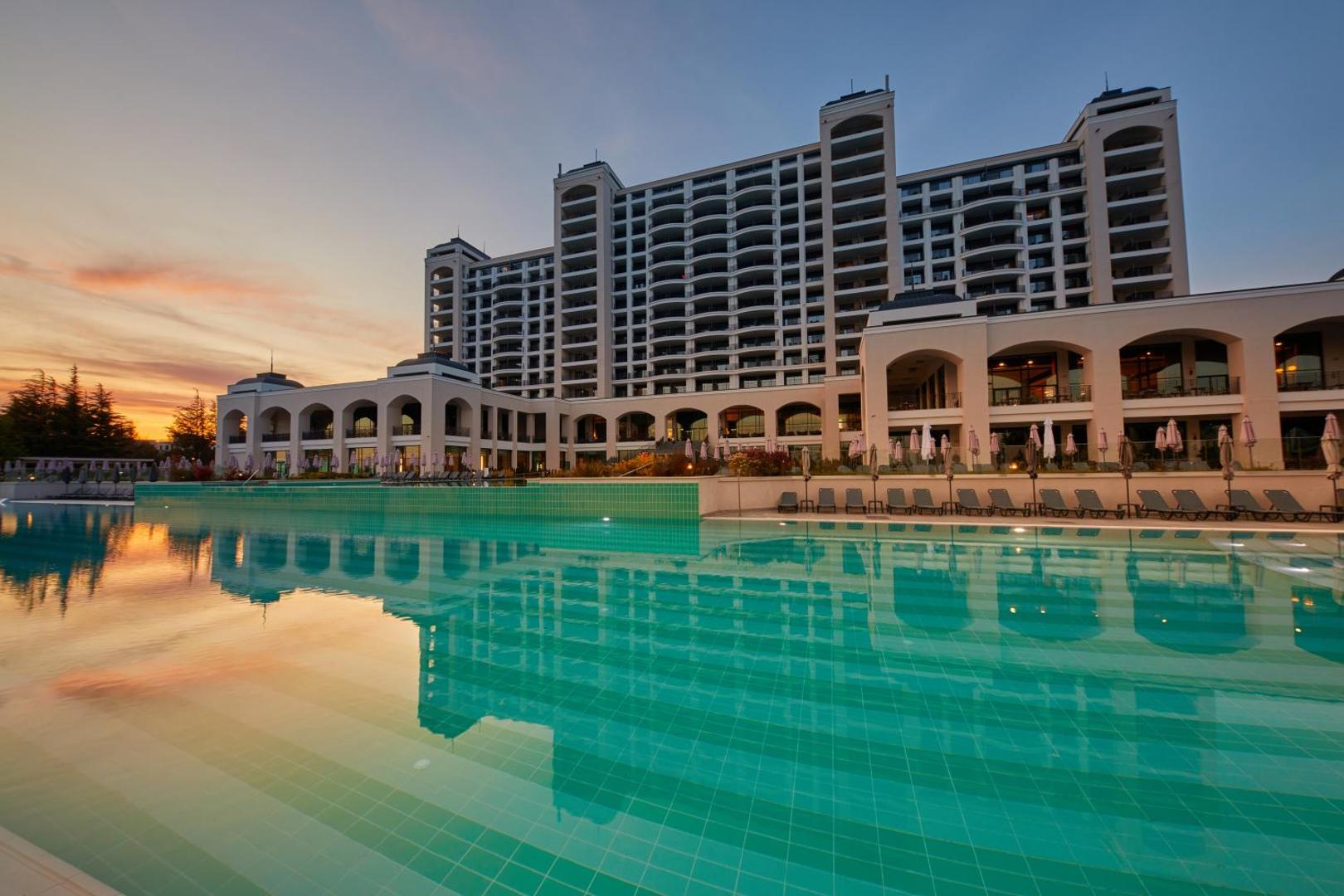 Secrets Sunny Beach Resort and Spa skats uz galveno ēku un plašo baseinu saulrieta laikā Saulainajā krastā