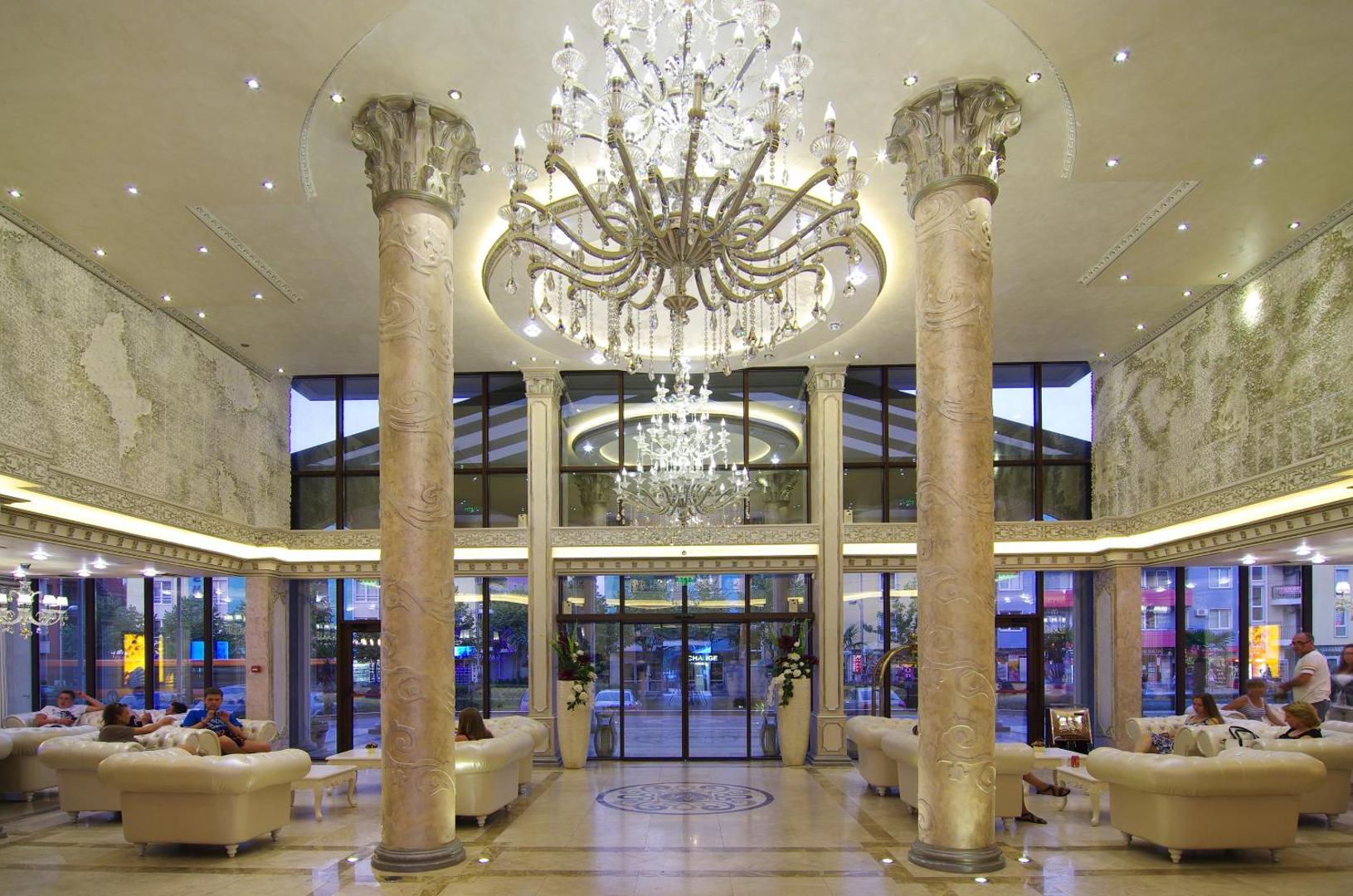 Diamant Residence Hotel & Spa greznais vestibils ar augstām kolonnām, masīvām lustrām un ērtiem ādas dīvāniem atpūtai