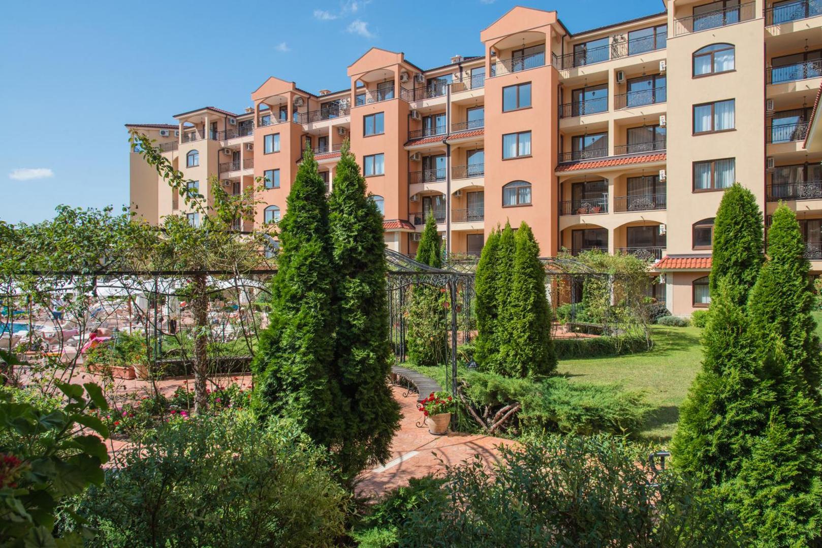 Diamant Residence Hotel & Spa dārzs ar zaļiem apstādījumiem un skatu uz viesnīcas balkoniem Saulainajā krastā