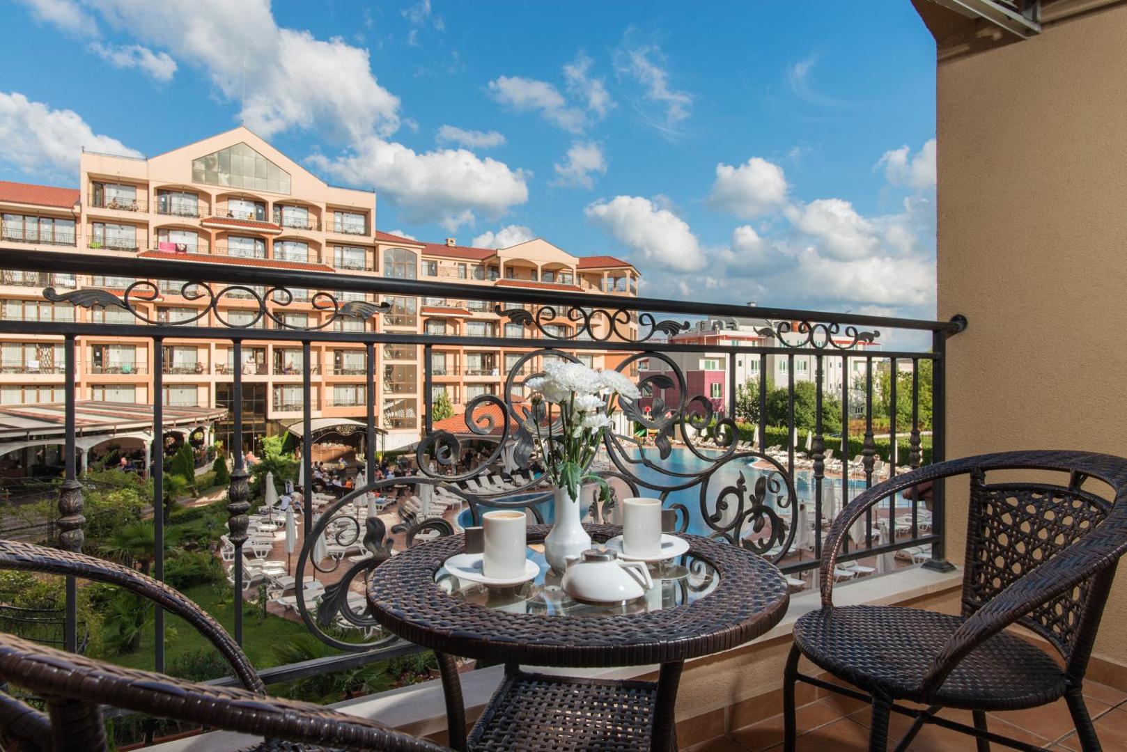 Diamant Residence Hotel & Spa numura balkons ar kafijas galdiņu, skats uz viesnīcas iekšpagalmu un baseinu Saulainajā krastā, Bulgārijā.