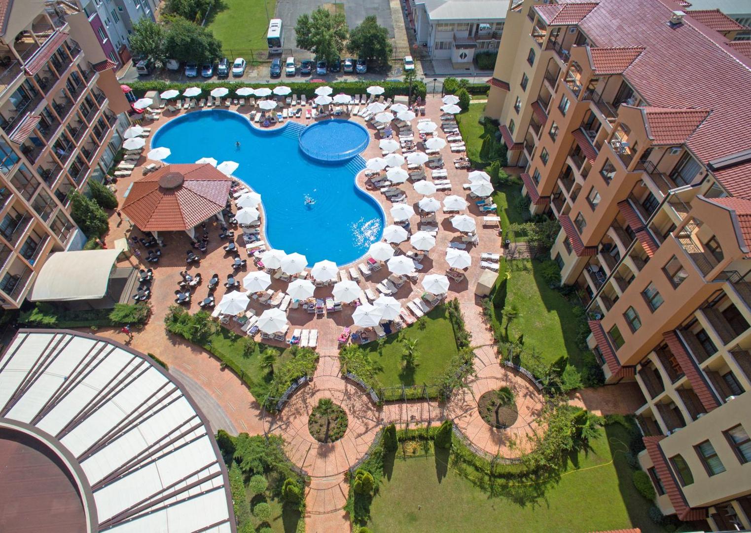 Diamant Residence Hotel & Spa skats no augšas uz baseinu kompleksu, saulessargiem un viesnīcas korpusiem Saulainajā krastā.
