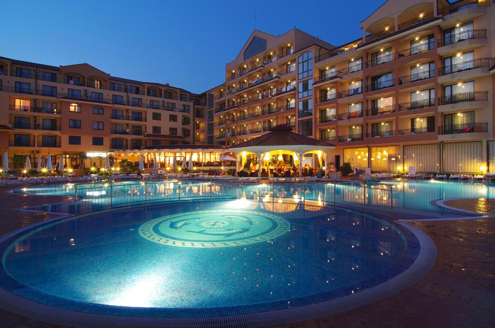 Diamant Residence Hotel & Spa izgaismots āra baseins vakarā Saulainajā krastā, Bulgārijā — viesnīcas fasāde ar balkoniem un baseina bāru