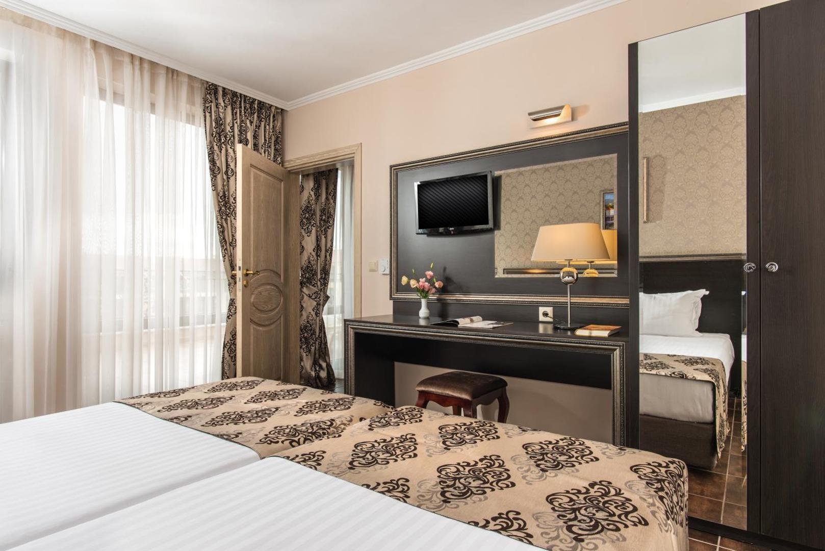 Diamant Residence Hotel & Spa divvietīgs numurs ar darba galdu, TV un lielu spoguļskapi, klasisks interjers siltos toņos.