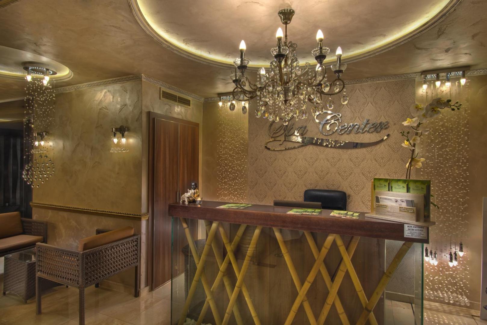 Diamant Residence Hotel & Spa greznā spa centra recepcija ar zeltītiem sienu dekoriem, kristāla lustru un bambusa apdares leti.
