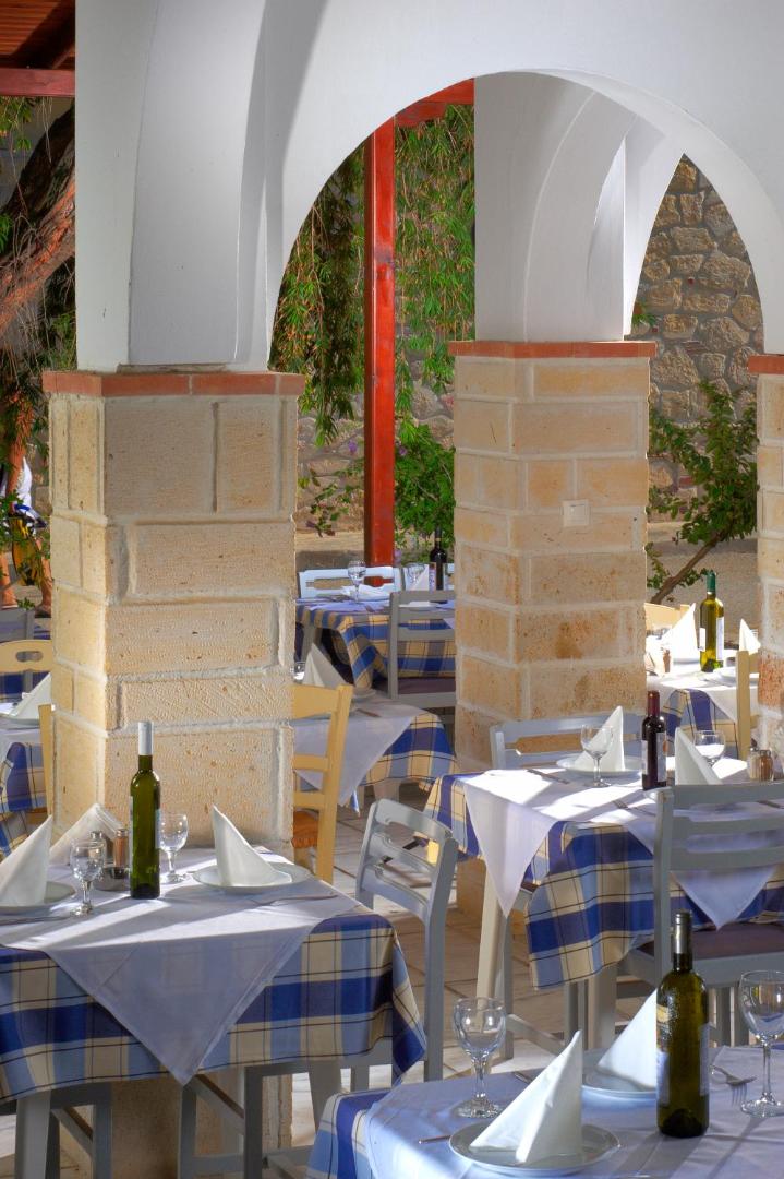Portes Beach Hotel grieķu taverna ar balti ziliem galdautiem zem arkām un skatu uz dārzu Halkidiki