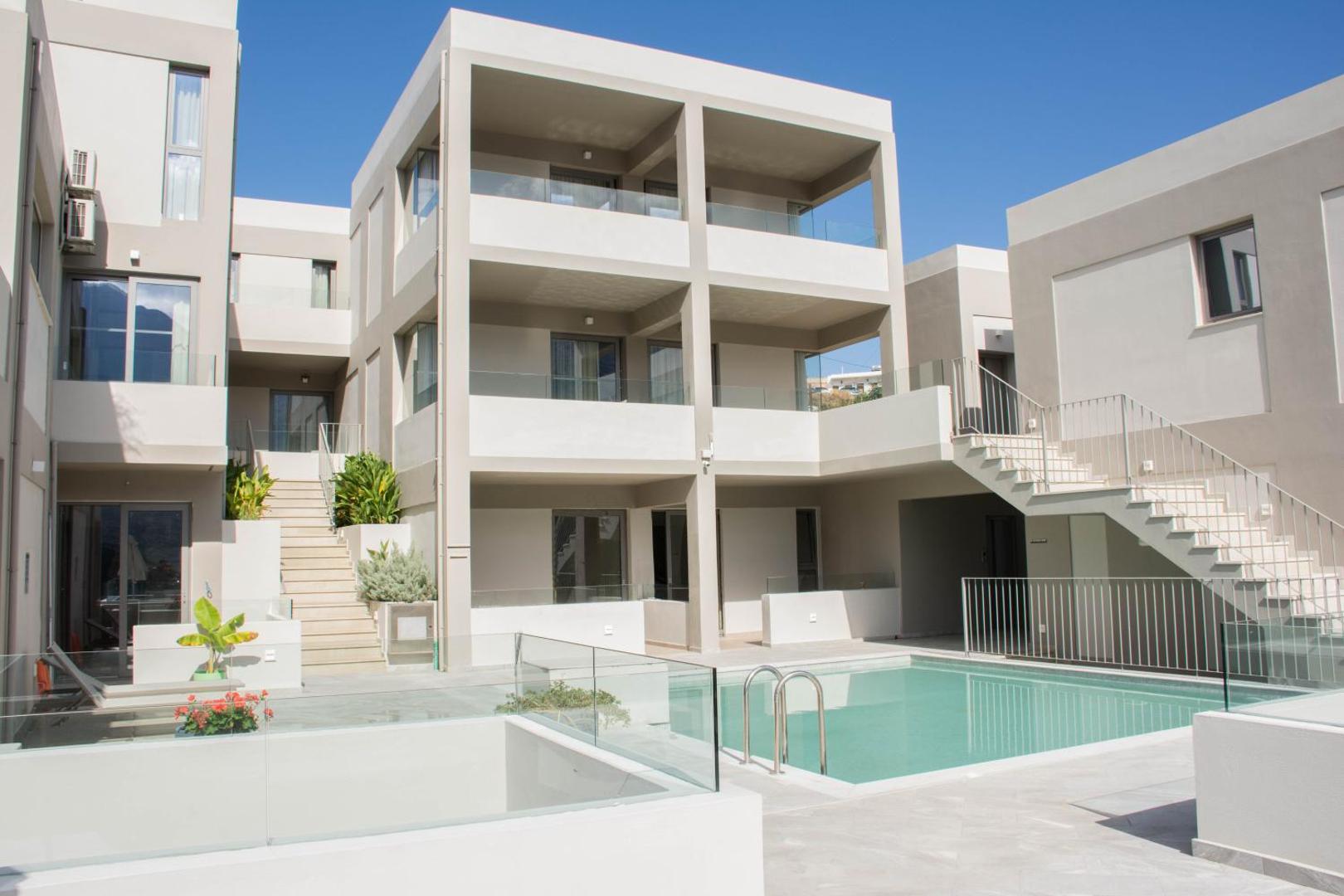 Bali Diamond Adults Only modernā arhitektūra un iekšpagalma baseins Krētā — gaišas ēkas ar balkoniem un stikla margām