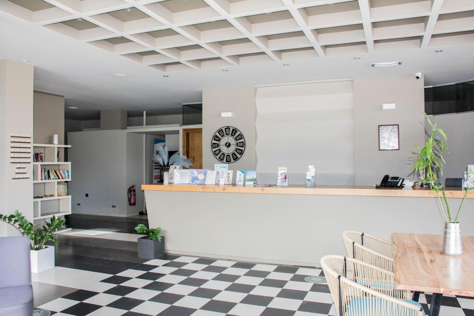 Bali Diamond Adults Only viesnīcas recepcijas zona ar gaišu koka leti, šaha raksta grīdu un modernu griestu dizainu Bali ciematā
