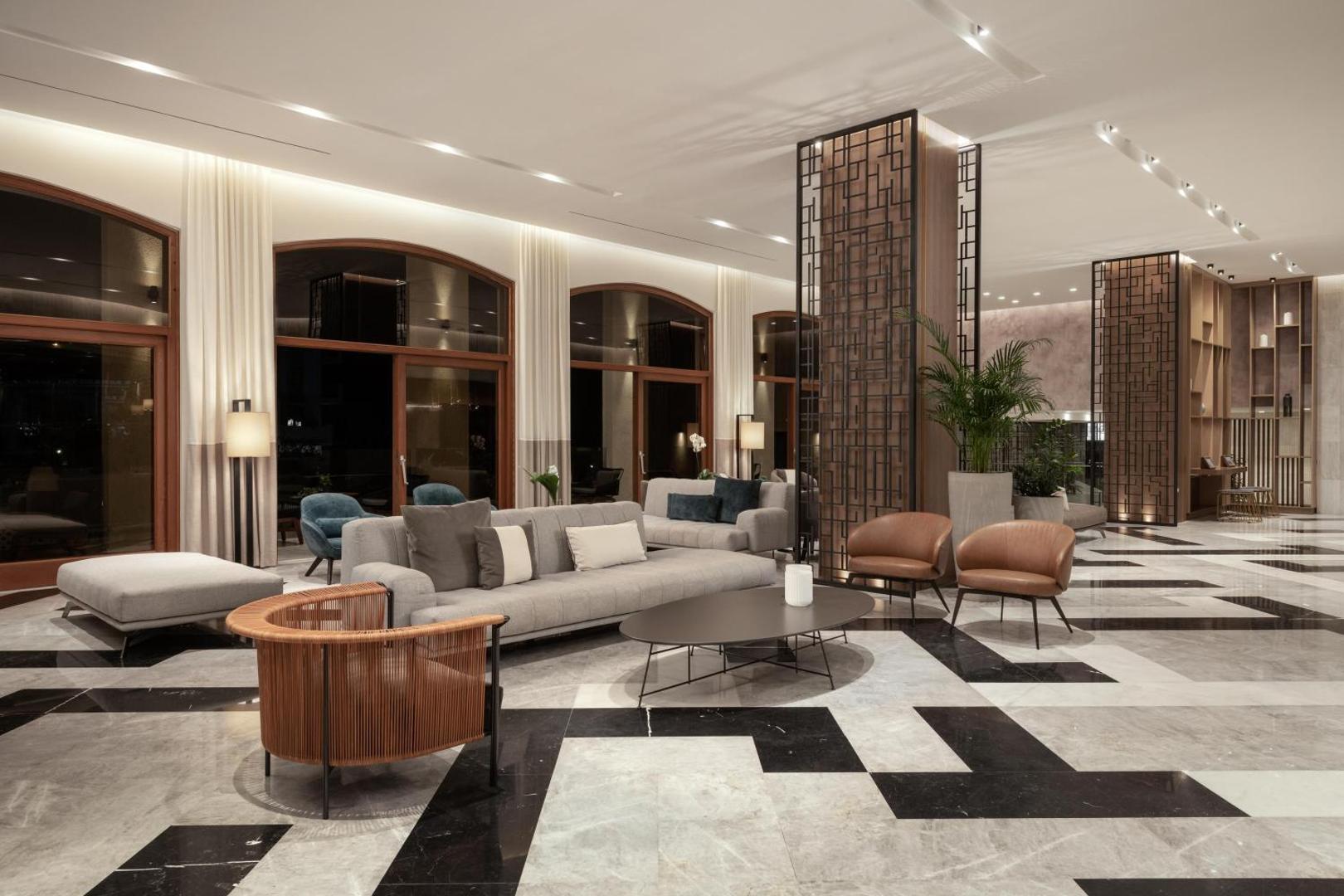 Theartemis Palace viesnīcas vestibils ar modernām mēbelēm, marmora grīdu un atpūtas zonu Retimno, Krētā — elegants interjers ar dīvāniem un krēsliem