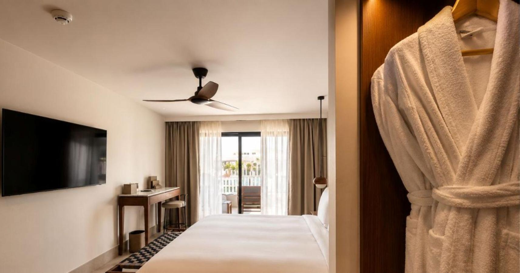 Vasia Hotel & Spa numura interjers ar skatu uz balkonu, TV un mīkstiem peldmēteļiem