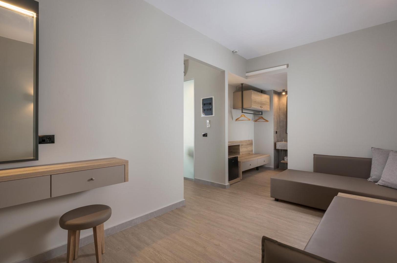 Mare Blue Suites numura interjers ar dīvānu, koka grīdu un lakonisku mēbeļu dizainu gaišos toņos