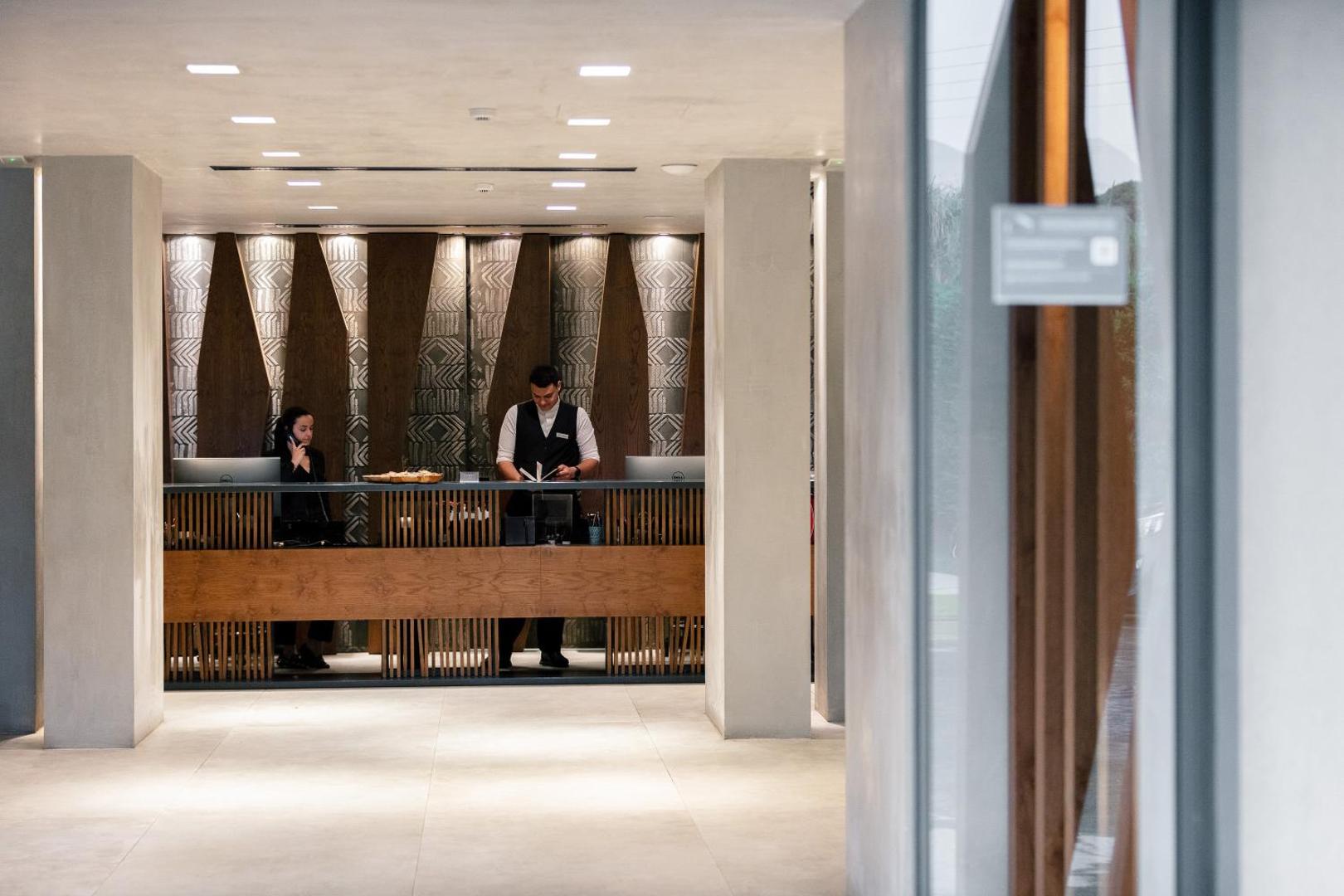 La Mer Resort & Spa recepcijas zona ar personālu un modernu koka apdari viesnīcas vestibilā Krētā