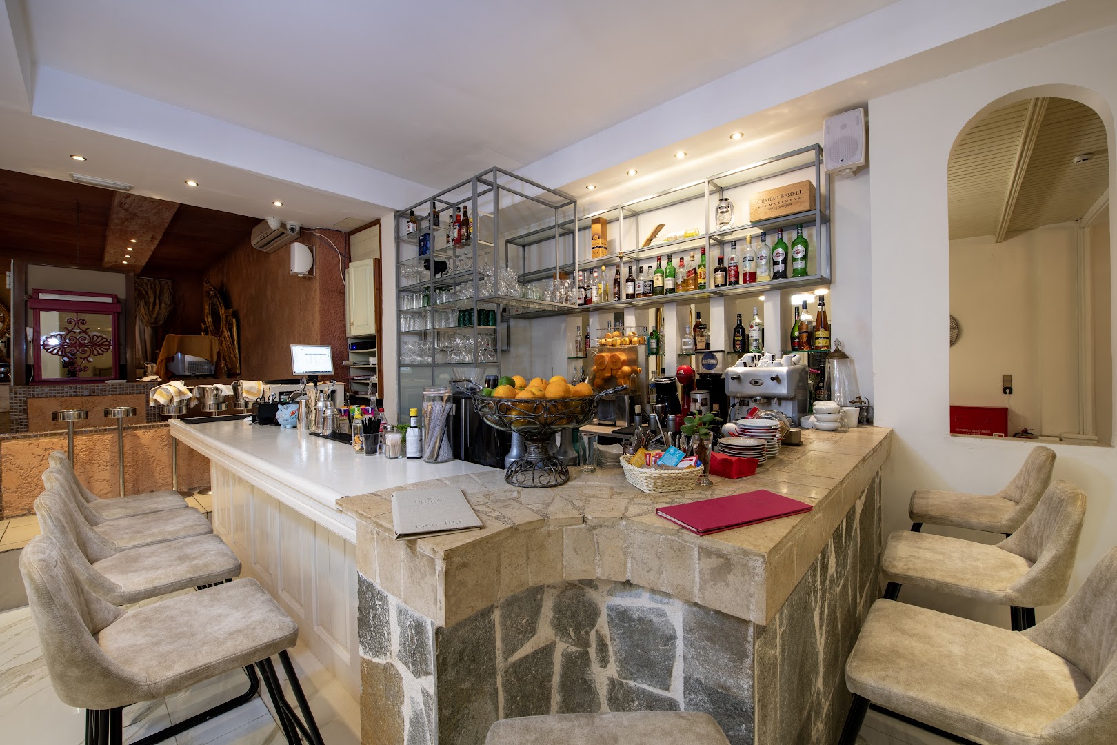 Orpheas Resort Hotel bārs ar akmens apdari, plašu dzērienu izvēli un ērtiem bāra krēsliem gaišā interjerā