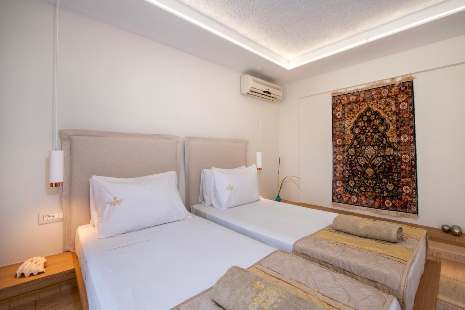 Orpheas Resort Hotel numurs ar divām atsevišķām gultām, gaišām sienām un dekoratīvu paklāju pie sienas Krētā