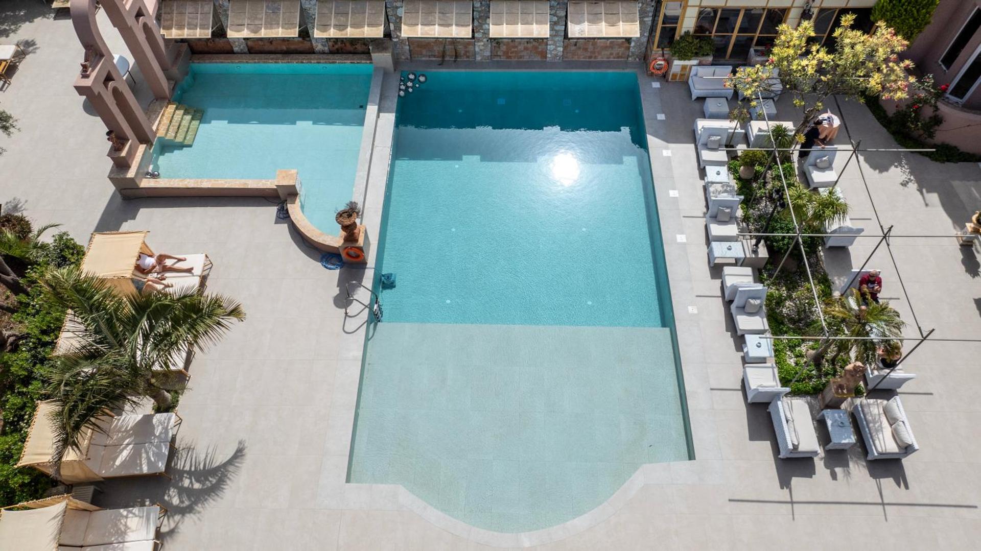 Orpheas Resort Hotel taisnstūra formas baseins ar atpūtas krēsliem un saulessargiem Georgiupoles reģionā, Krētā