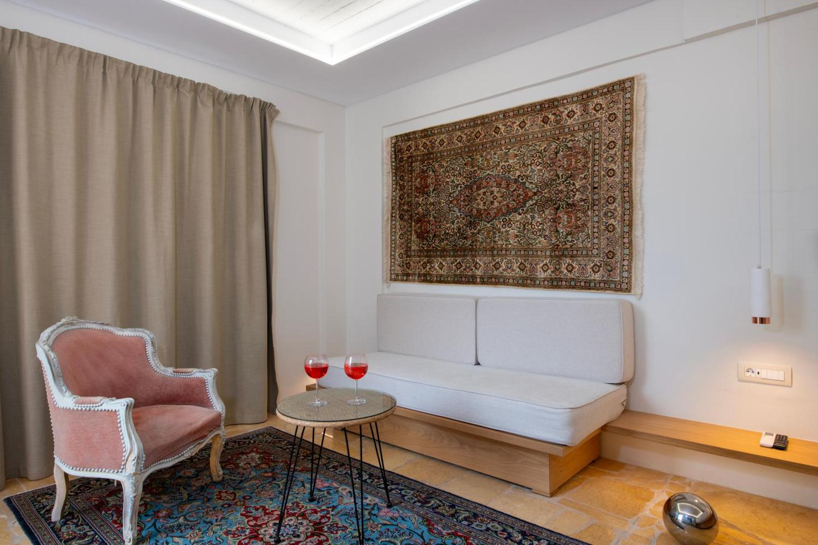 Atpūtas stūris Orpheas Resort Hotel numurā ar rozā velveta krēslu, nelielu galdiņu un austrumu paklāju