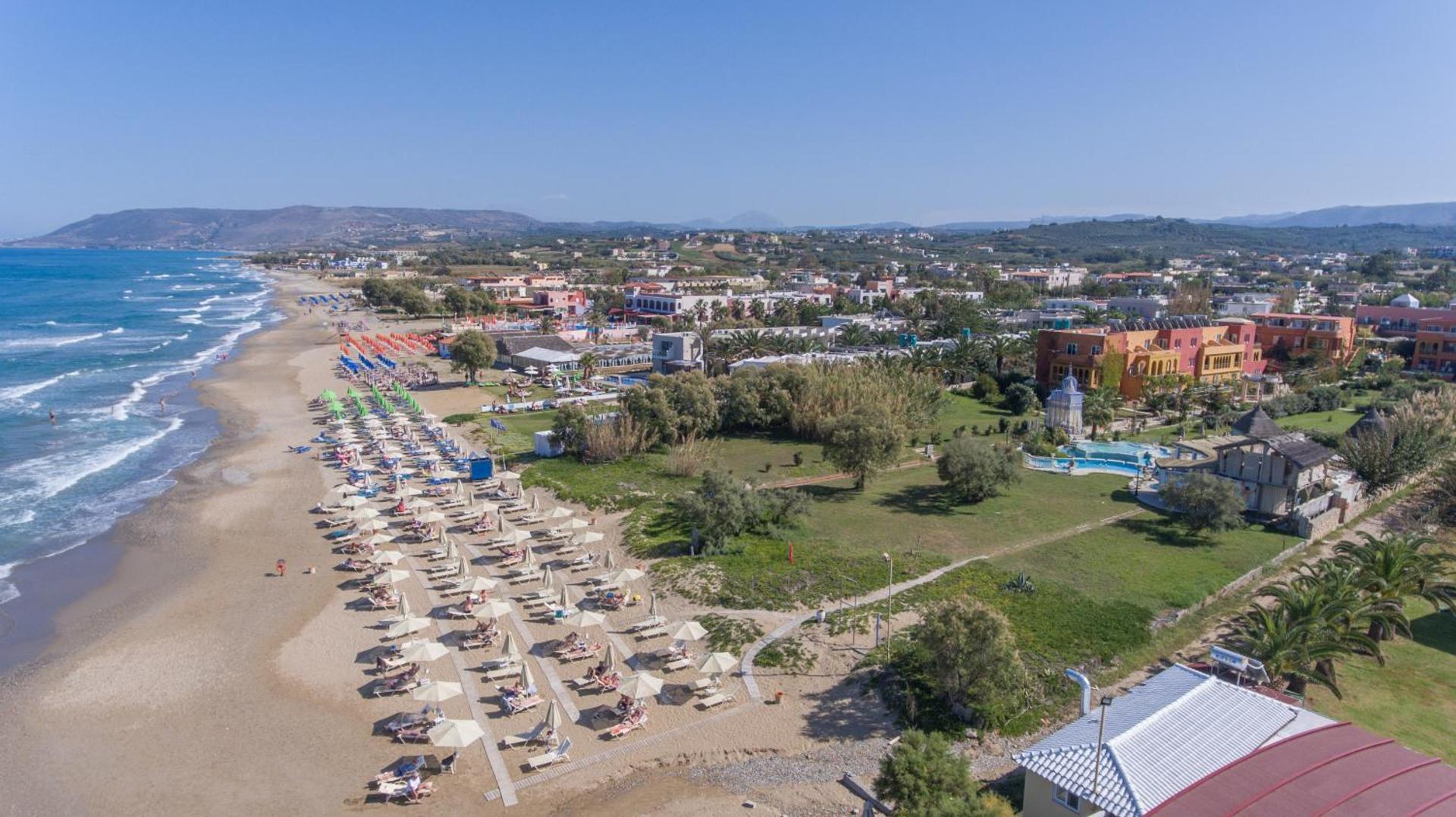 Orpheas Resort Hotel skats no putna lidojuma uz plašo smilšu pludmali, saulessargiem un viesnīcas dārzu piekrastē Krētā