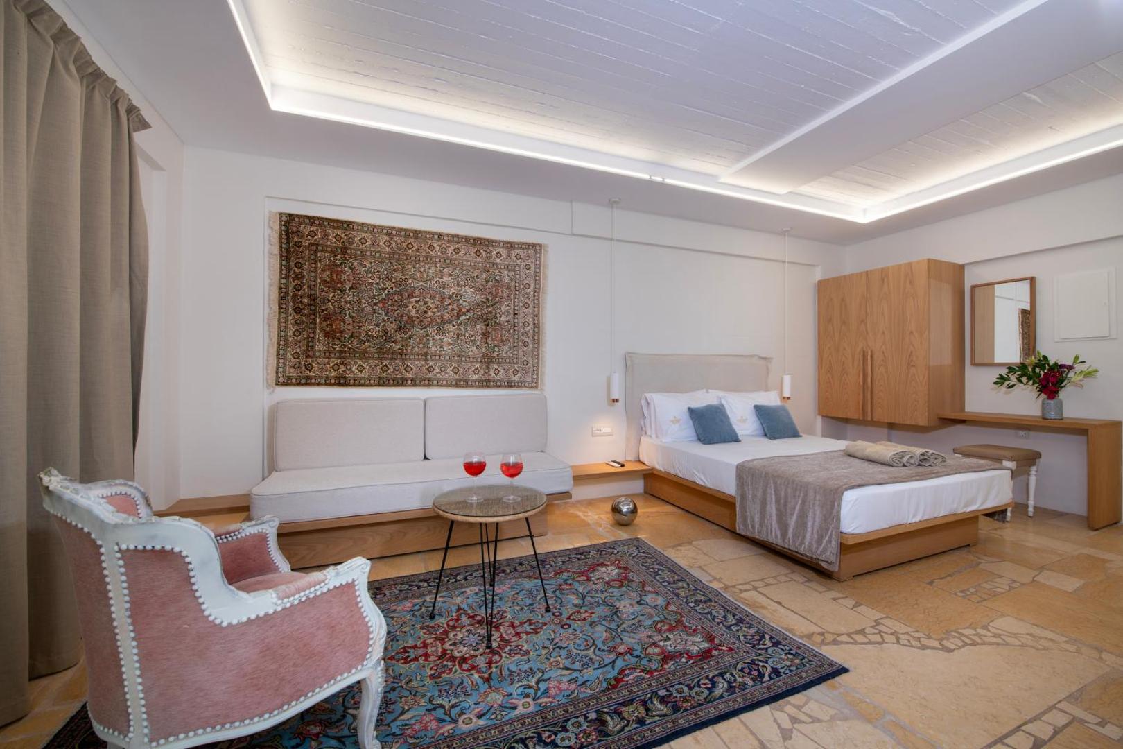Orpheas Resort Hotel plašs numurs ar divguļamo gultu, atpūtas zonu, antīka stila krēslu un austrumu paklājiem Krētā