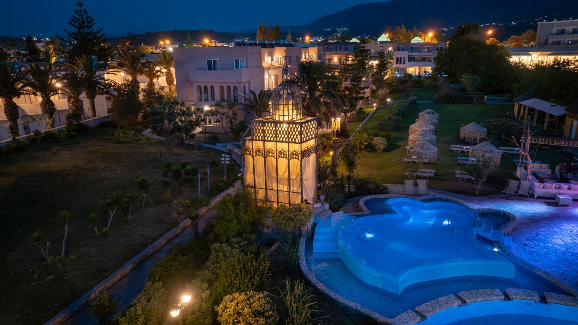 Orpheas Resort Hotel nakts skats uz izgaismotu baseinu un viesnīcas ēkām Georgiupoles kūrortā, Krētā