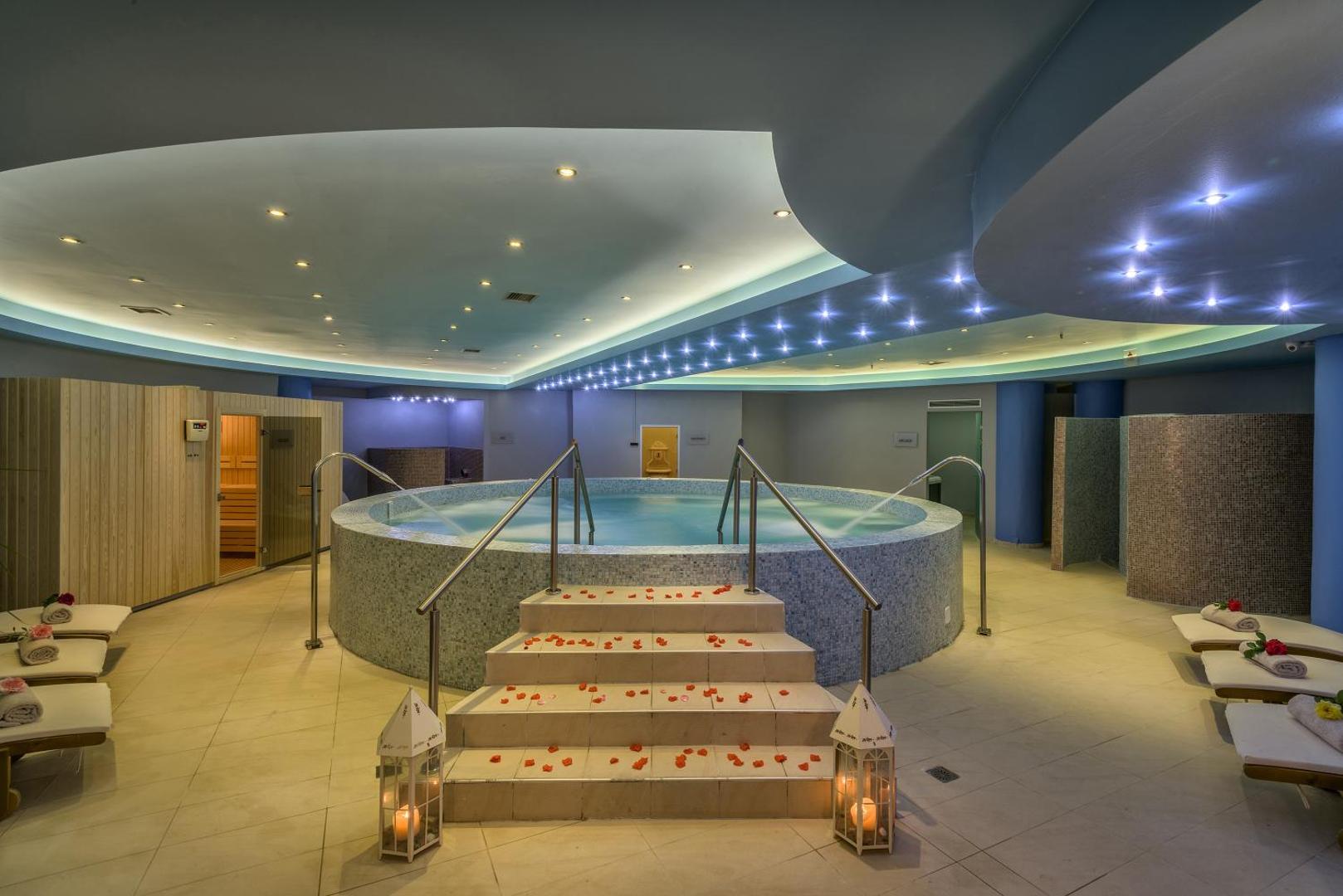 Georgioupolis Resort Aqua Park and SPA spa centrs ar apsildāmu baseinu, saunu un relaksācijas krēsliem mierīgā atmosfērā