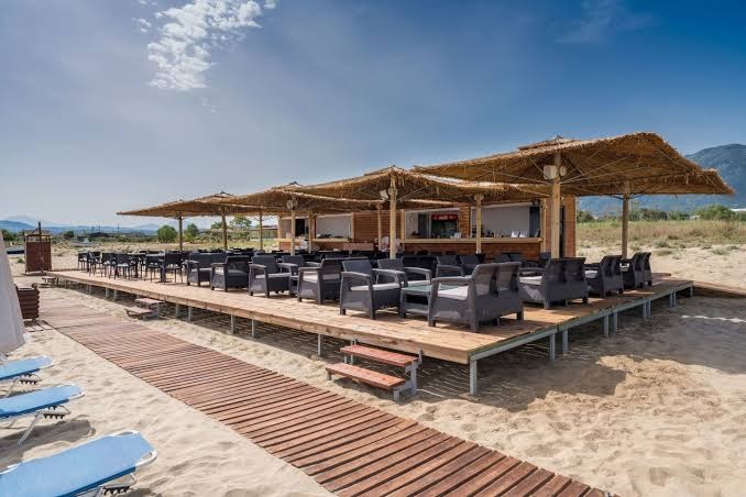 Georgioupolis Resort Aqua Park and SPA pludmales bārs ar salmu jumtiem un koka terasi smilšainajā piekrastē Krētā