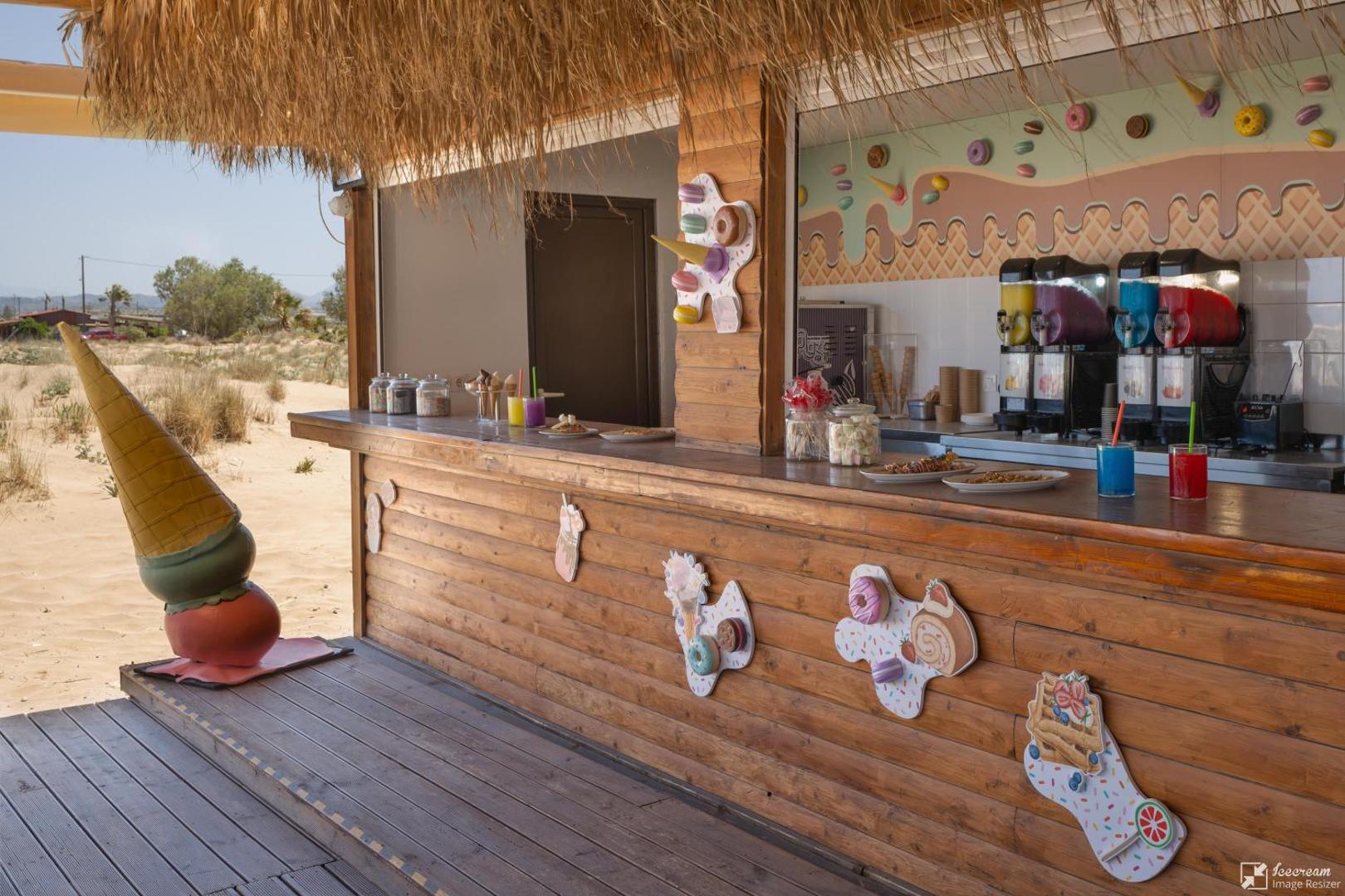 Georgioupolis Resort pludmales bārs ar salmu jumtu un saldējuma dekorācijām — uzkodu un dzērienu vieta tieši pie jūras