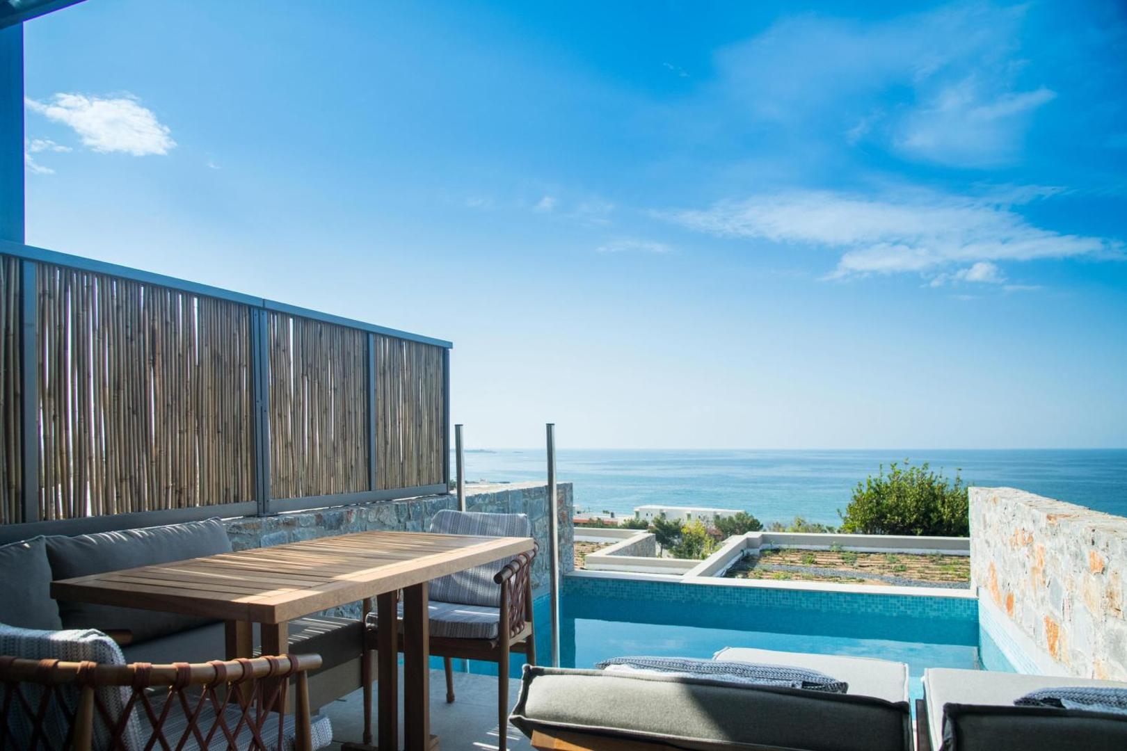 King Minos Retreat Resort & Spa terase ar koka galdu un skatu uz jūru — numurs ar tiešu piekļuvi baseinam un stikla norobežojumu