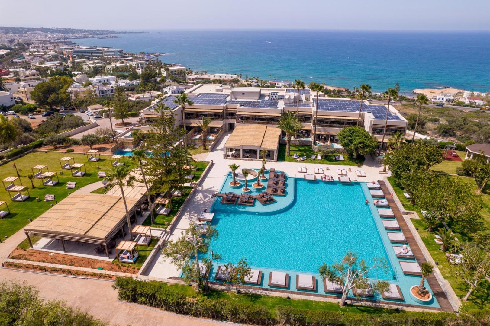 King Minos Retreat Resort & Spa panorāmas skats no putna lidojuma uz lielo āra baseinu, viesnīcas ēku un Vidusjūras piekrasti Hersonisā