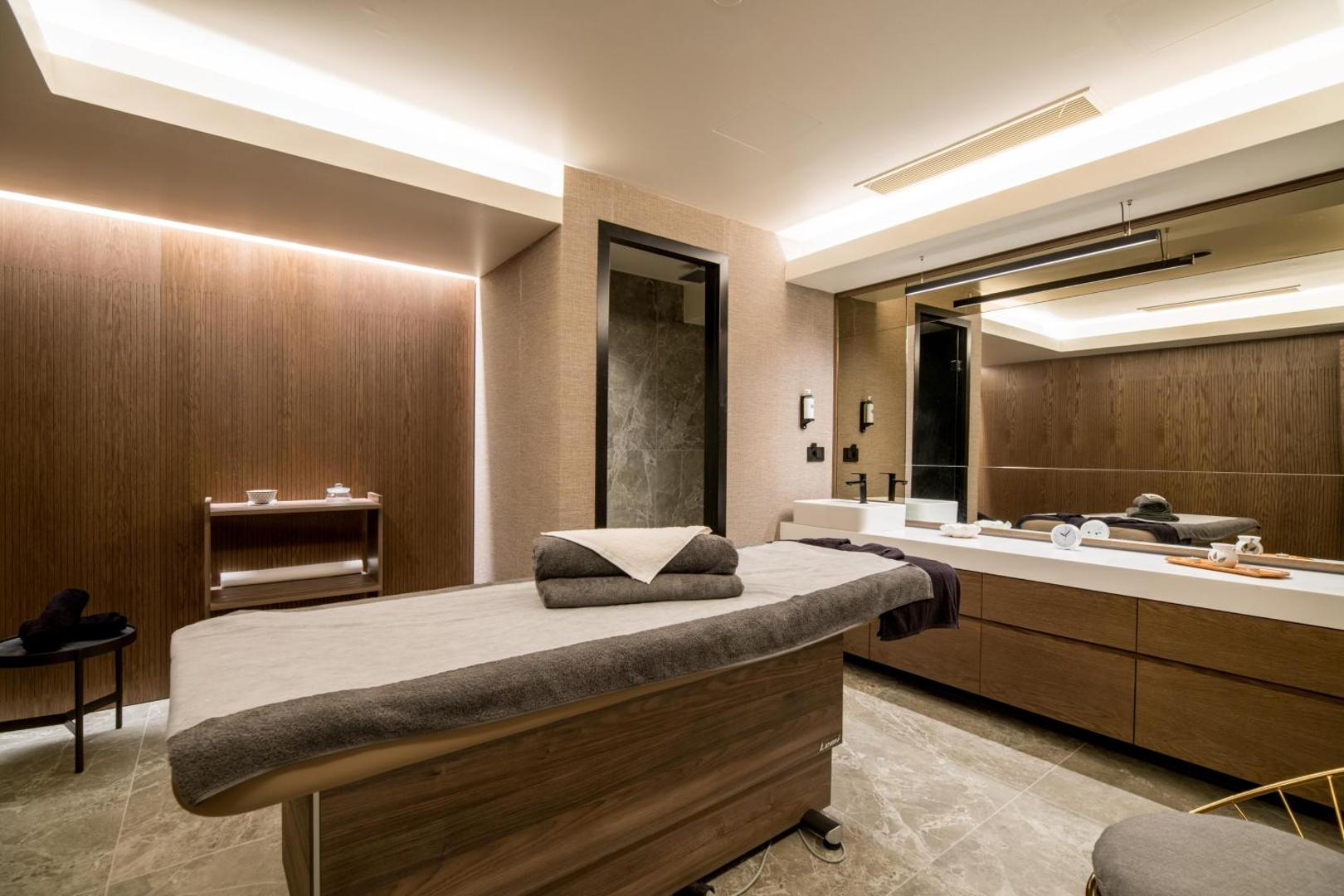 King Minos Retreat spa centra masāžas telpa ar koka apdari, profesionālu galdu un siltu apgaismojumu relaksācijai