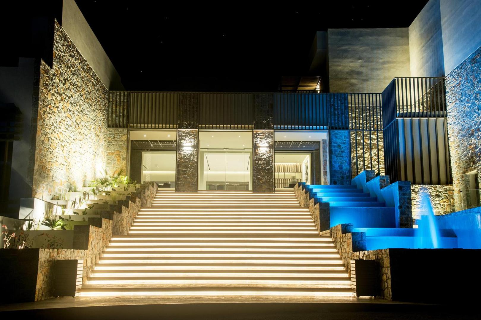 King Minos Retreat Resort & Spa galvenā ieeja naktī ar izgaismotām kāpnēm un modernu arhitektūru Hersonisā, Krētā