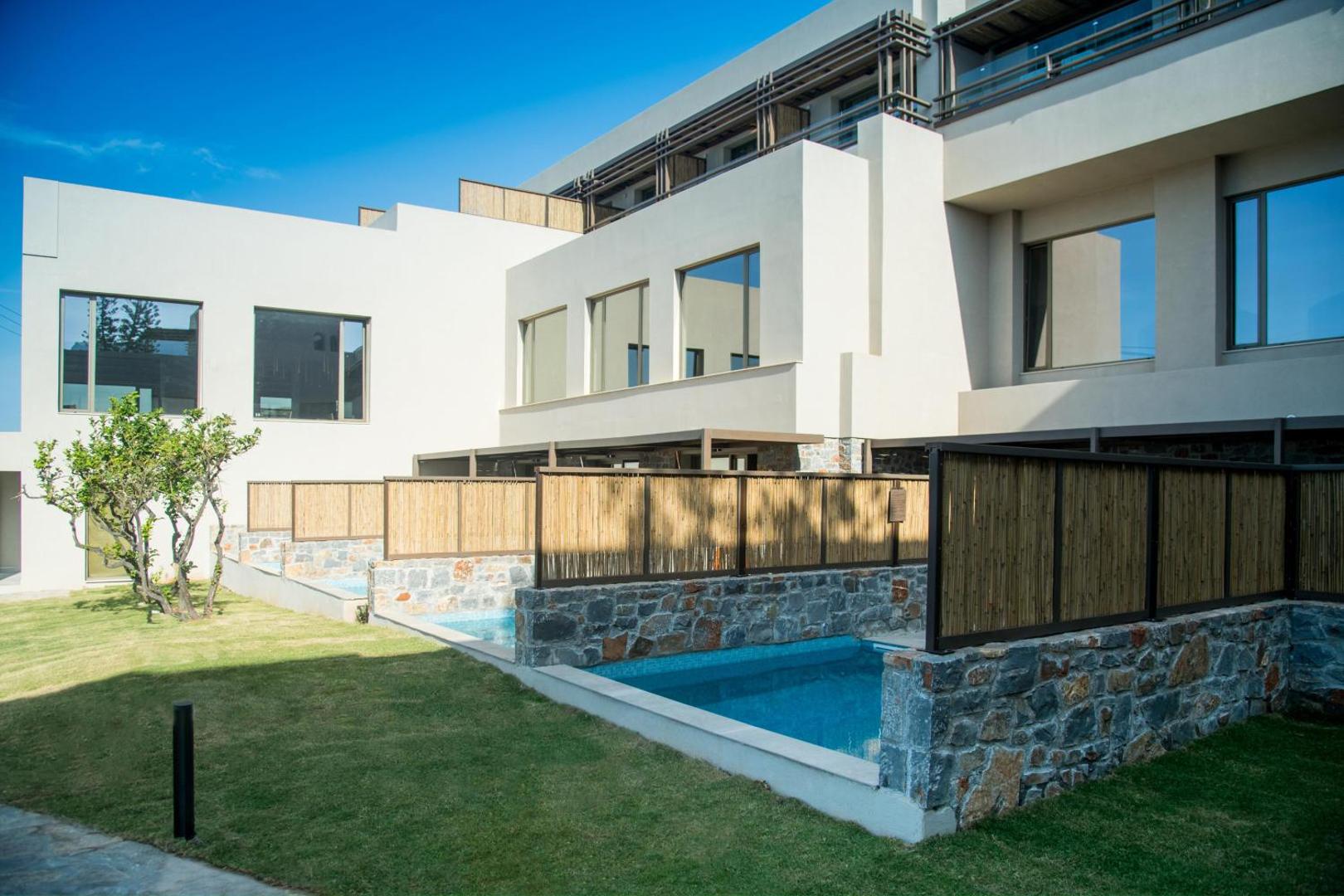 King Minos Retreat Resort & Spa numuri ar tiešu piekļuvi baseinam un privātām terasēm, ko ieskauj akmens mūra sienas