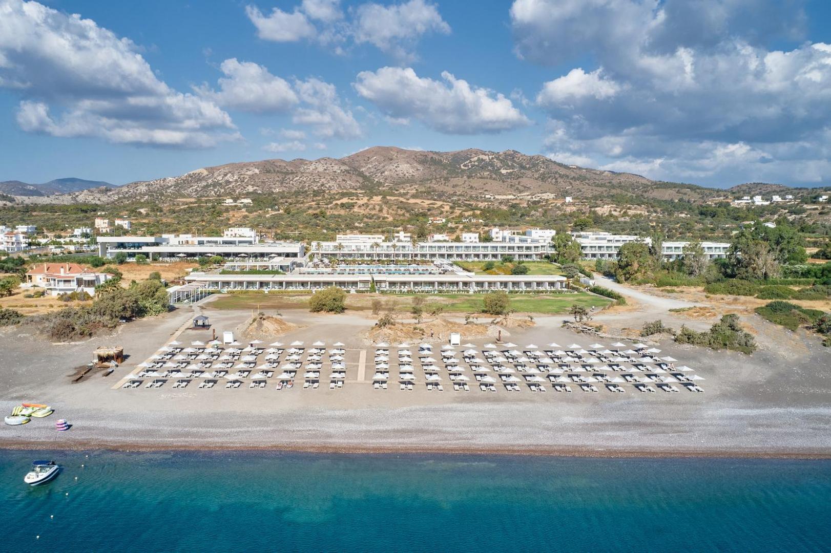 Gennadi Grand Resort panorāmas skats no jūras puses uz viesnīcas korpusiem, pludmales zonu un kalniem fonā Rodā