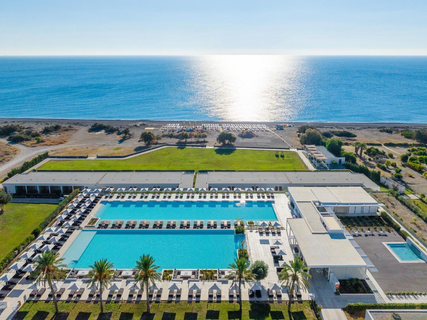 Gennadi Grand Resort skats no augšas uz lielajiem āra baseiniem un privāto pludmali Rodas salas dienvidos saulainā dienā