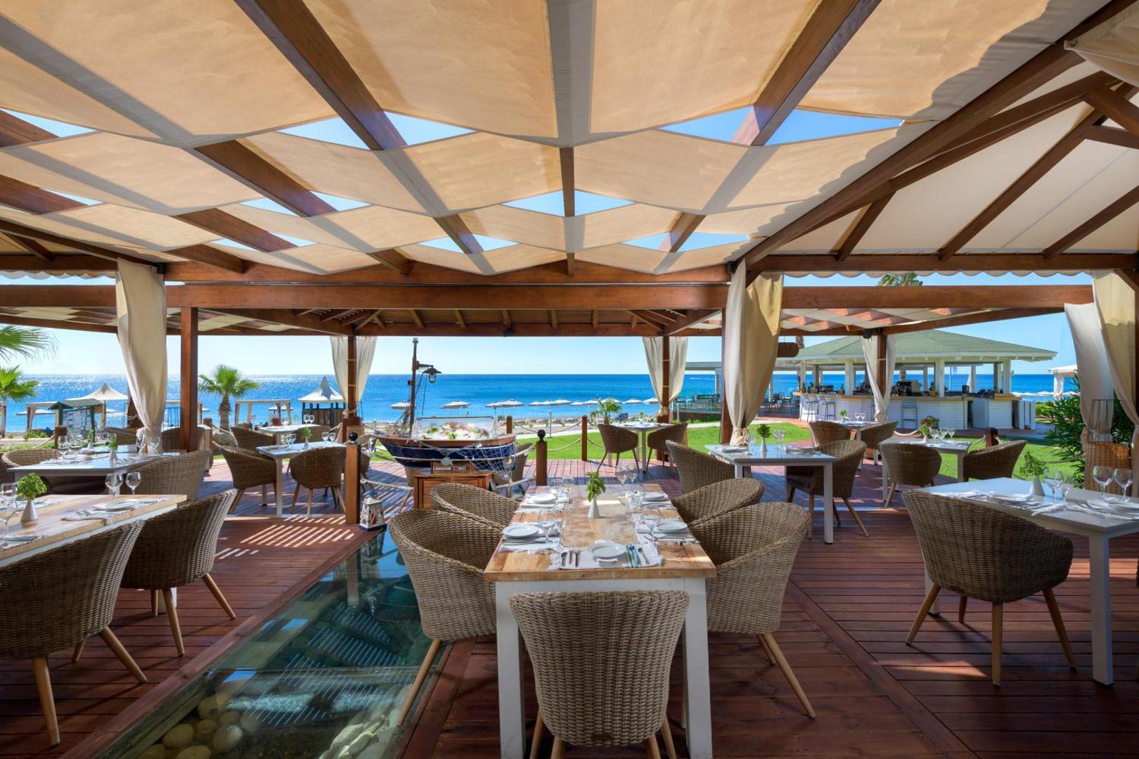 Rodos Palladium Leisure & Wellness āra restorāns ar koka apdari un skatu uz pludmali Rodas salā
