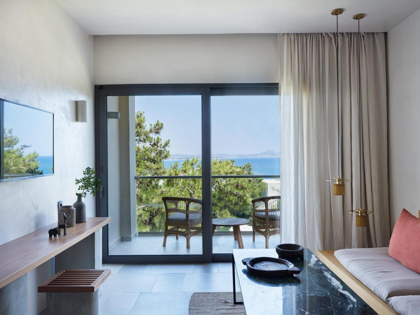 Sentido Port Royal Villas & Spa numura interjers ar skatu uz jūru un priedēm, balkons ar mēbelēm un eleganta atpūtas zona