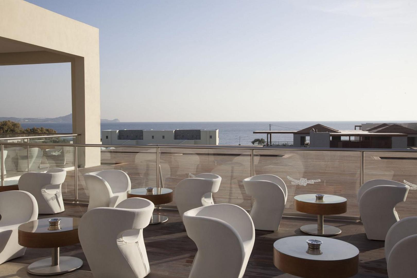 Sentido Port Royal Villas & Spa āra bāra terase ar moderniem baltiem krēsliem un skatu uz Vidusjūru