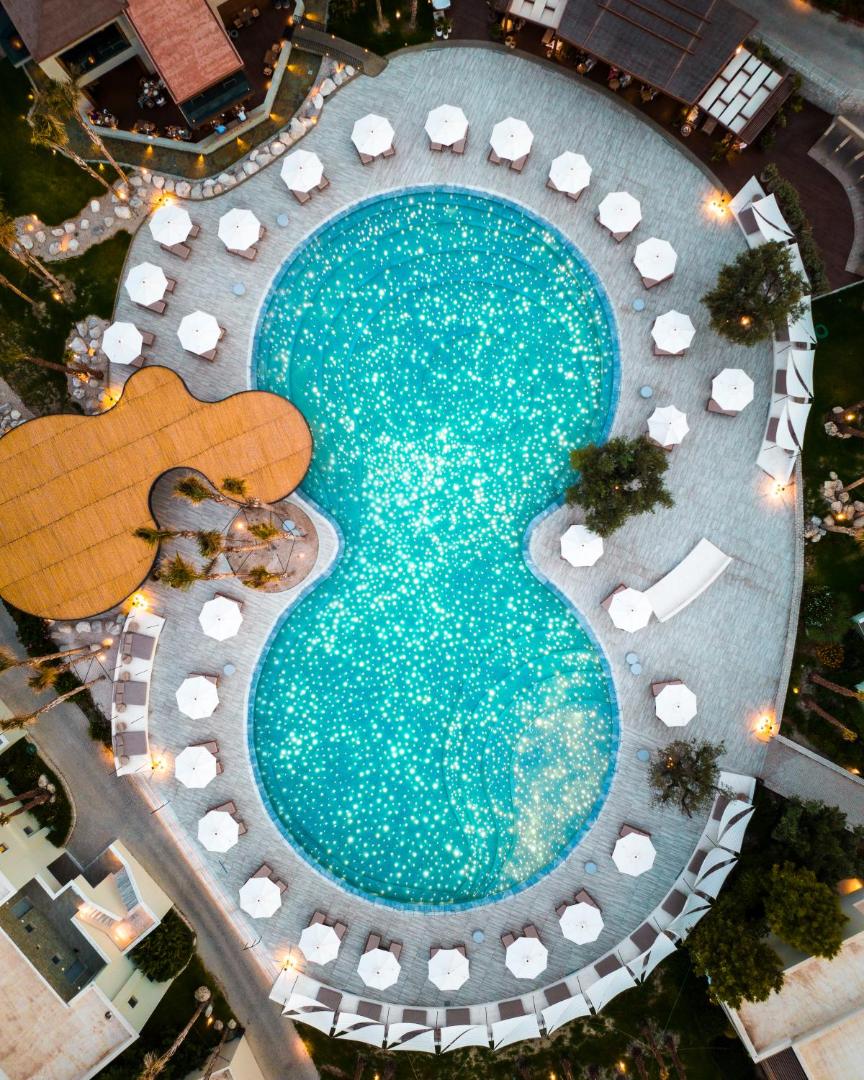 Sentido Port Royal Villas & Spa baseina skats no putna lidojuma ar zvaigžņotu apgaismojumu ūdenī un saulessargiem