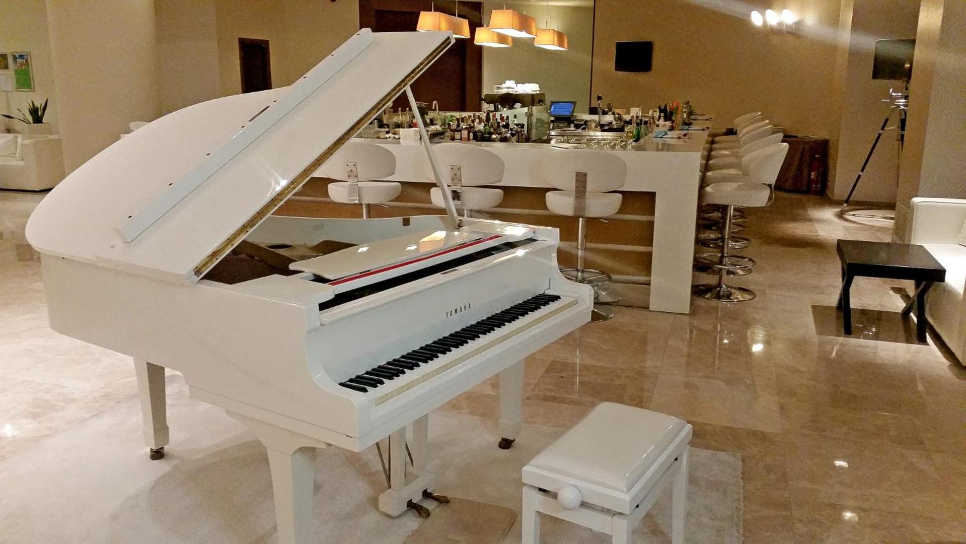 Sentido Port Royal Villas & Spa balts flīģelis viesnīcas vestibila bārā — elegants interjers ar bāra leti un baltiem krēsliem