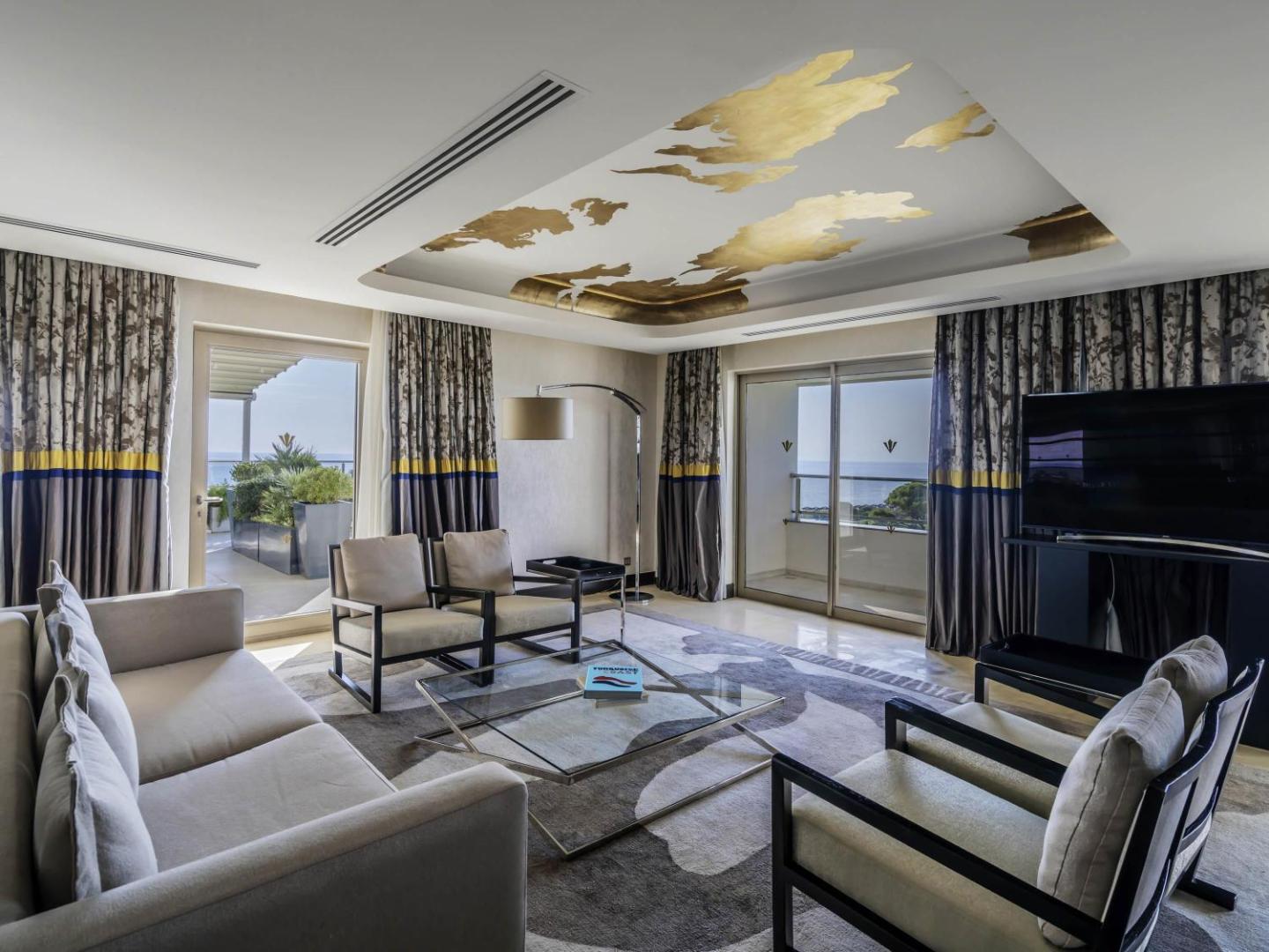 Rixos Premium Belek plašs viesistabas numurs ar modernām mēbelēm, zelta griestu dekoru un skatu uz jūru no balkona