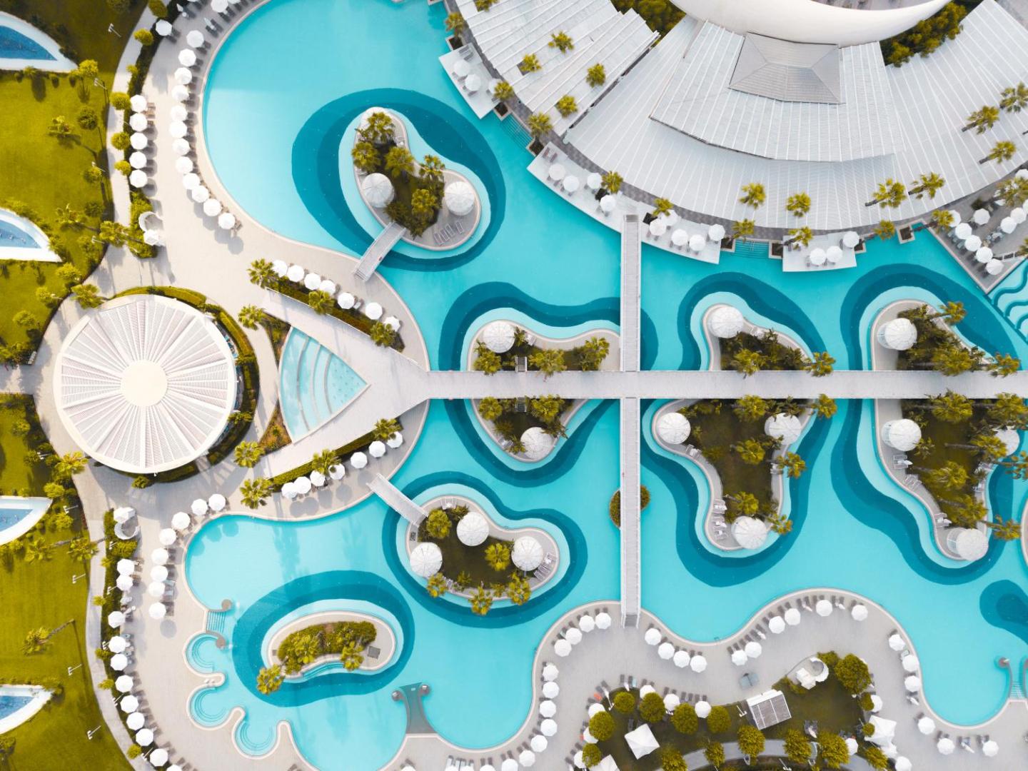 Sueno Hotels Deluxe Belek skats no putna lidojuma uz plašo baseinu kompleksu ar salām, tiltiņiem un atpūtas zonām Belekā