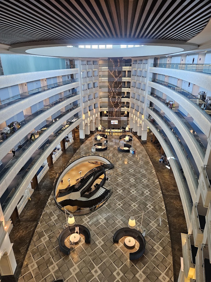 Sueno Hotels Golf Belek iespaidīgais daudzstāvu ātrijs un vestibils ar modernām kāpnēm, atpūtas zonām un rakstainu marmora grīdu