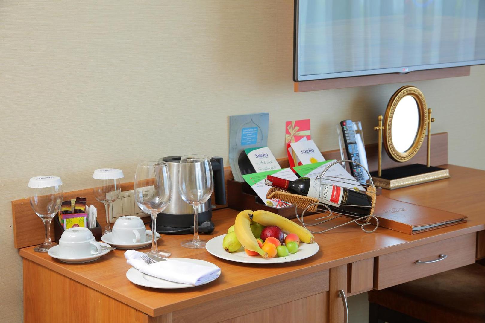 Viesnīcas Sueno Hotels Golf Belek numura sagaidīšanas komplekts ar augļiem, vīnu, tējas pagatavošanas piederumiem un spoguli uz koka galda
