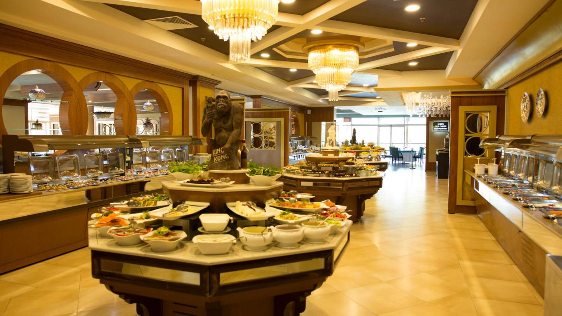 Sueno Hotels Golf Belek galvenā restorāna bufetes zona ar plašu uzkodu un salātu izvēli, greznām lustrām un modernu interjeru
