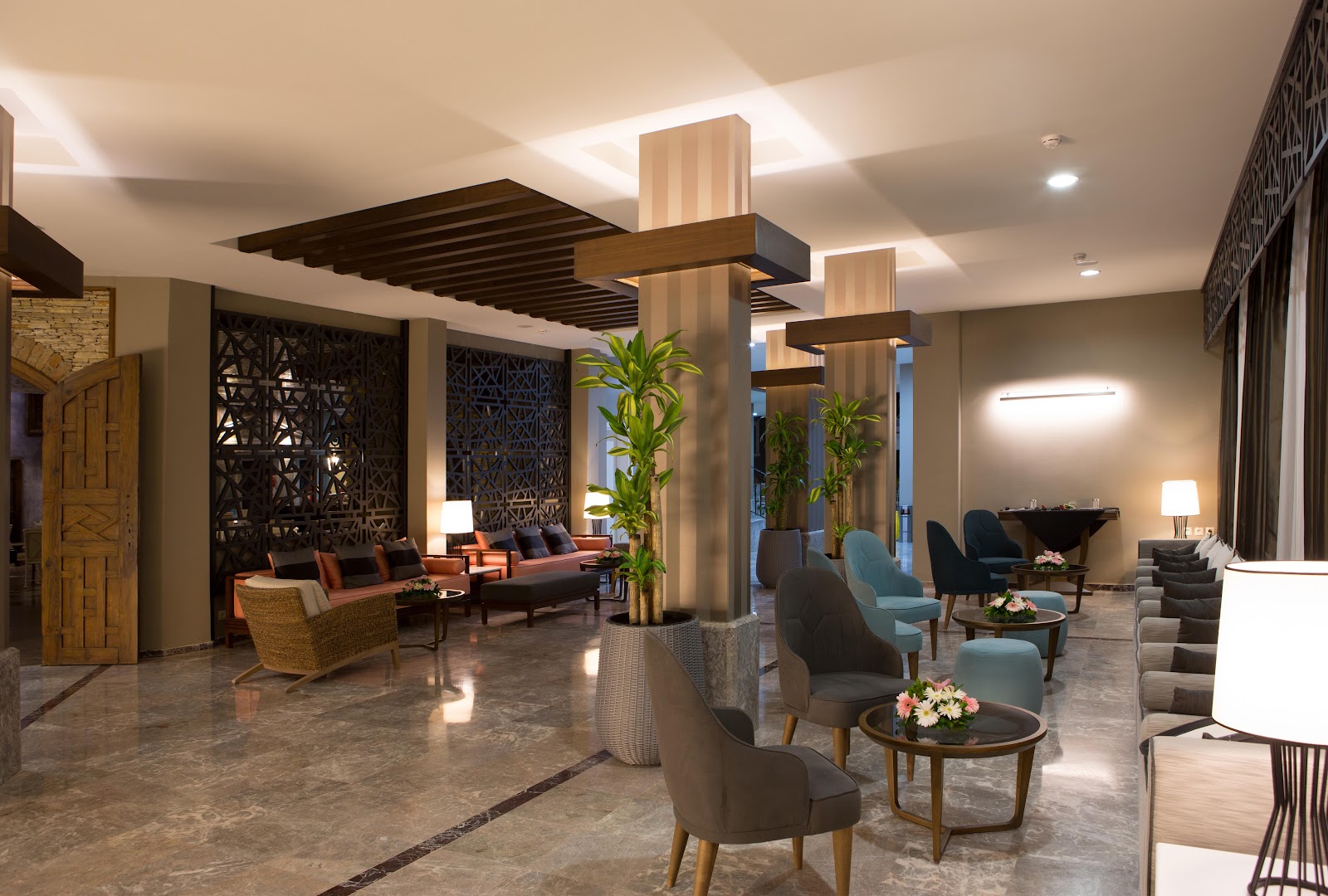 Paloma Marina Suites viesnīcas lobby interjers ar krāsainiem atpūtas krēsliem, dekoratīvām sienām un telpaugiem mājīgai gaisotnei