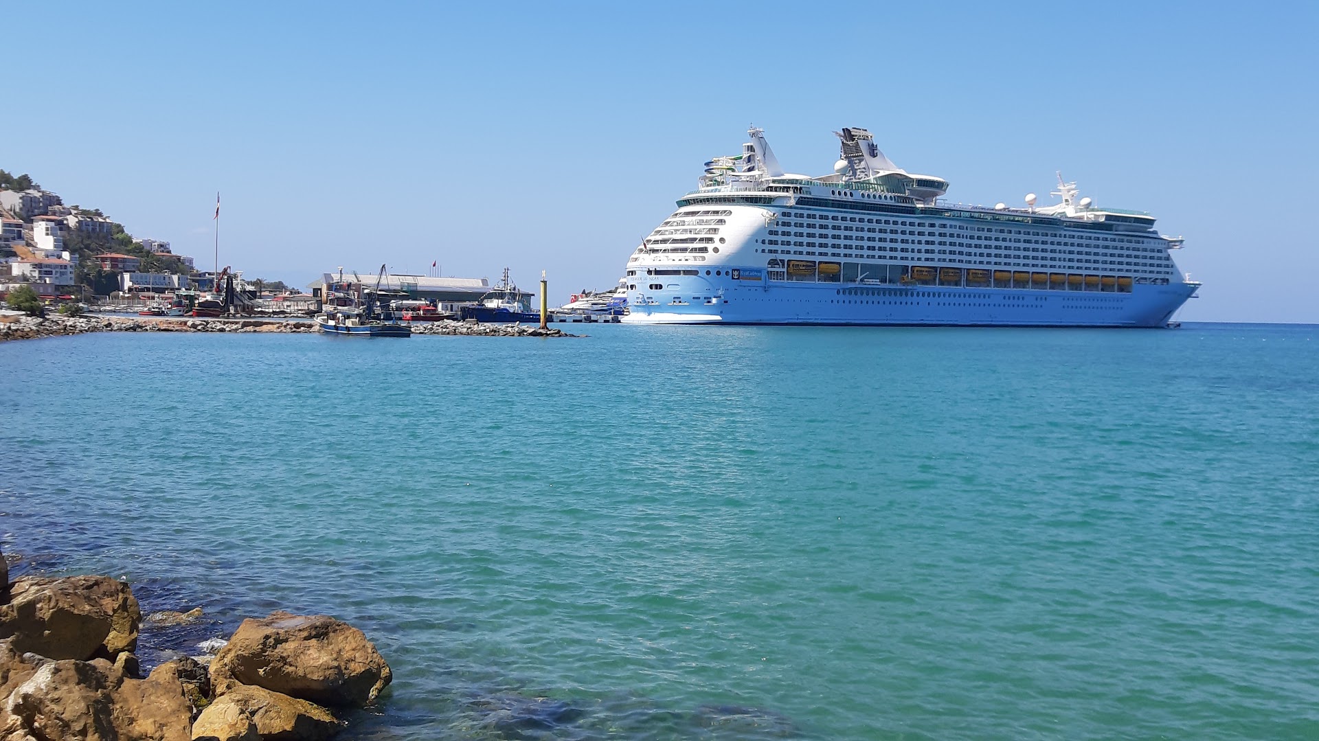 Paloma Marina Suites skats uz Kusadasi ostu un lielo kruīza kuģi dzidri zilā Egejas jūras ūdenī saulainā dienā